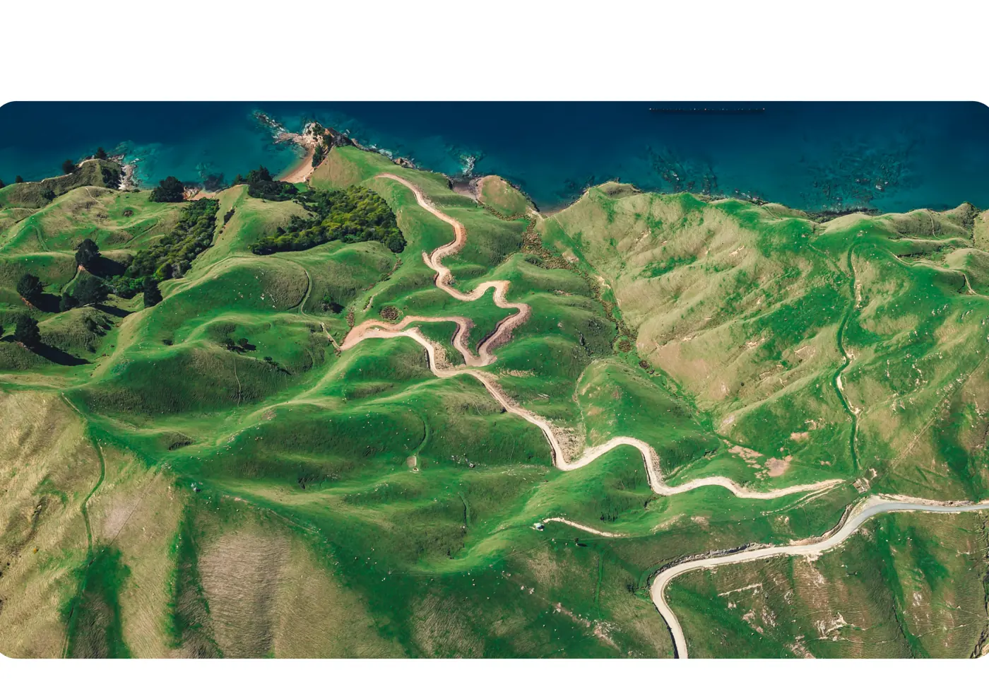 Paisagem aérea verde com estradas sinuosas perto da costa